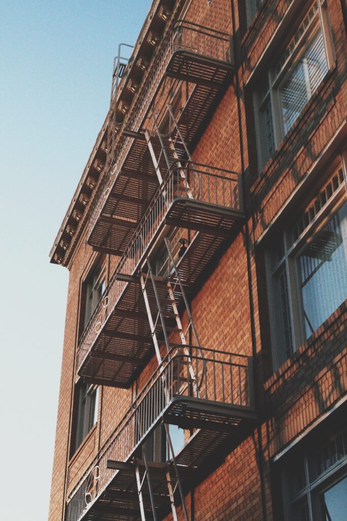 Vertical low-angle shot of an old brick building with the emergency exit staircase on the side